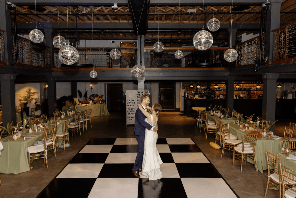 Cam and Sarah dancing alone on a black and white checkered dance floor in an empty venue